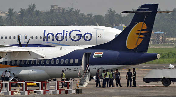 Staff stand next to parked passenger jets of IndiGo and Jet Airways (front) at Kolkata airport.