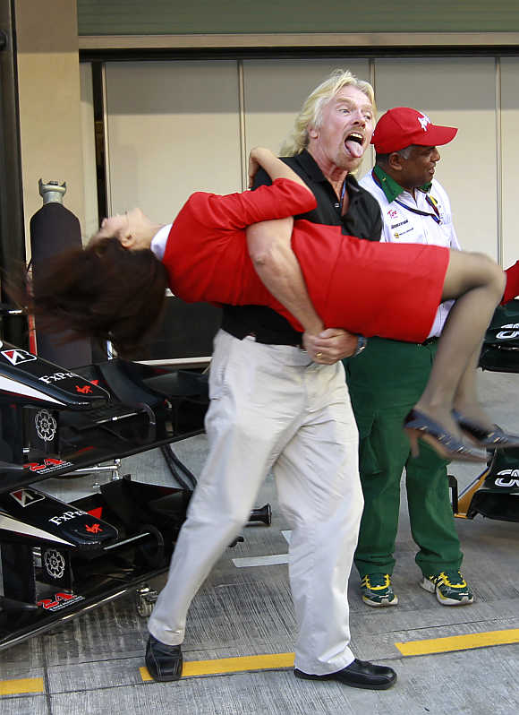 Richard Branson carries a stewardess before the qualifying session for the Abu Dhabi F1 Grand Prix at Yas Marina circuit in Abu Dhabi.