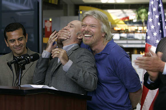 Richard Branson covers the mouth of Virgin Blue Group Co-Founder and Chief Executive Officer Brett Godfrey during a news conference with Los Angeles Mayor Antonio Villaraigosa in Los Angeles, California.