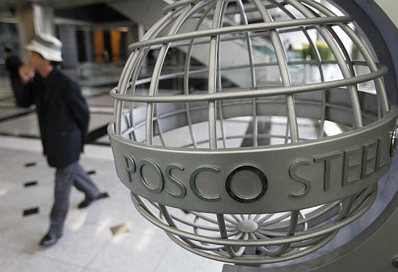 A man walks past a logo of steelmaker Posco at the company's headquarters in Seoul, South Korea.
