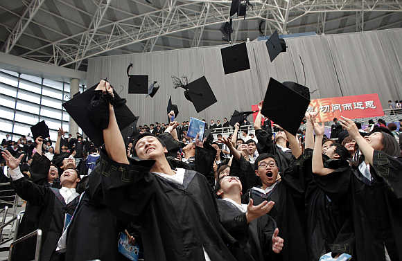 Graduates throw their mortar boards into the air after their graduation ceremony at Fudan University in Shanghai.