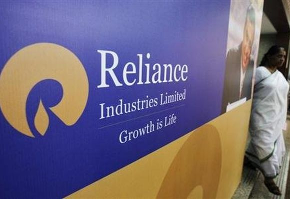 A woman walks past a poster of Reliance Industries.