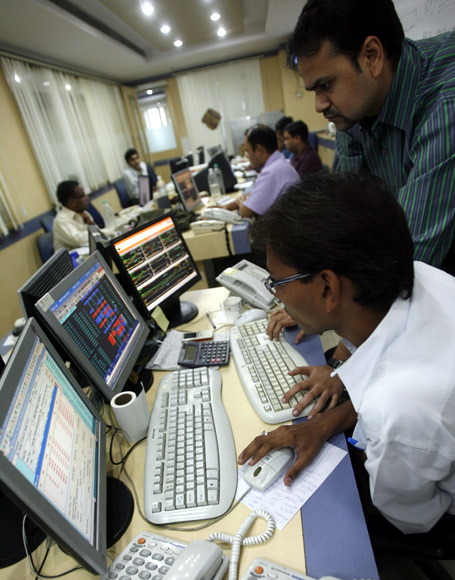Traders look at their computer screens while trading at a stock brokerage firm in Mumbai.