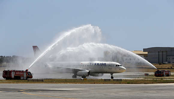 A Turkish Airlines Airbus A320 aircraft is welcomed to Malta by a water arch created by two airport fire fighting vehicles at Malta International Airport outside Valletta.