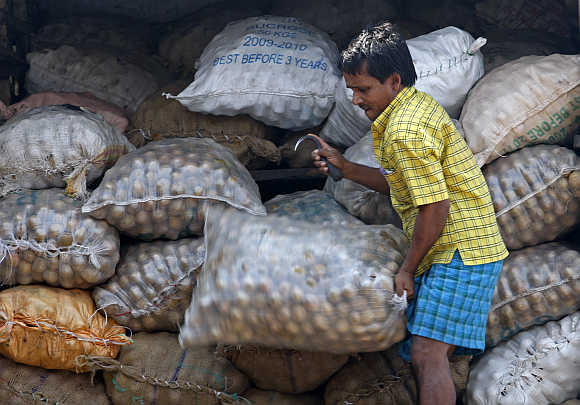 A worker unloads a sack of fruit from a truck at a wholesale market in Mumbai.