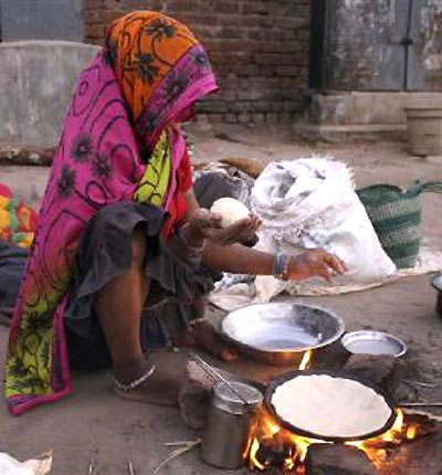  homeless woman prepares food on a roadside in Ahmedabad.