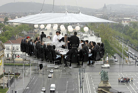 Journalists have lunch 'in the sky' around a table lifted by a crane above Heroes Square in Budapest.