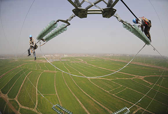 Electricians check the electricity pylon situated amid farmland in Chuzhou, Anhui province, China.