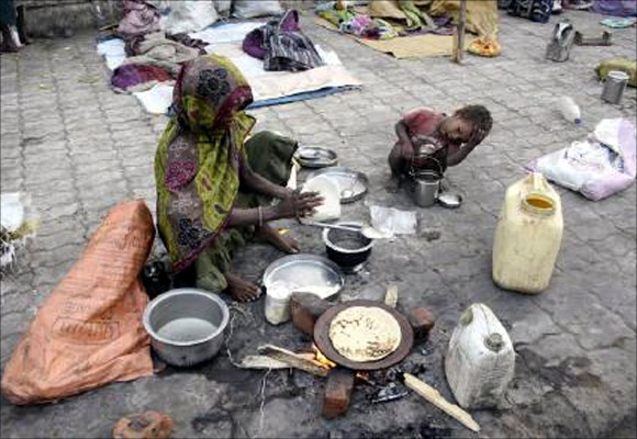 A homeless woman prepares food on the footpath.
