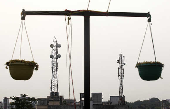 Telecommunication towers are pictured through hanging flower pots at a residential building in Kolkata.