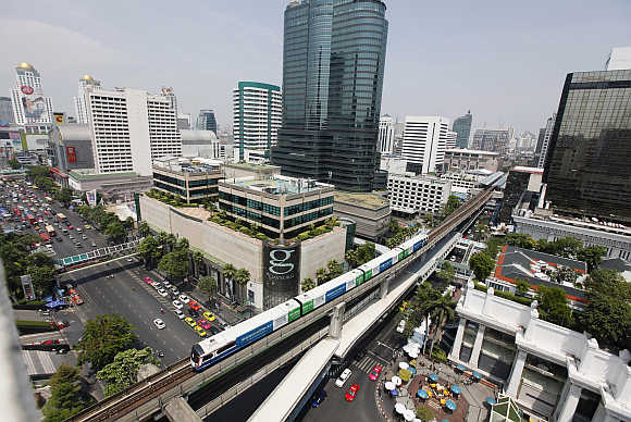 A skytrain passes over vehicles on road in Bangkok.