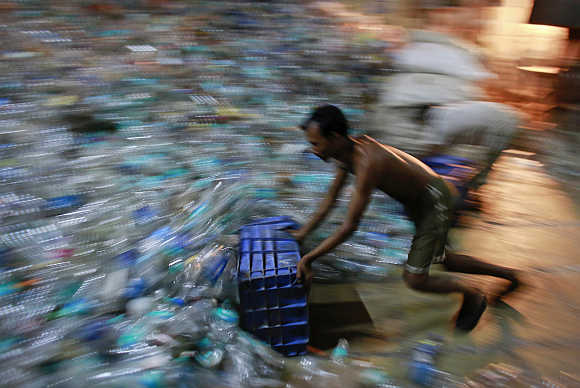 A man collects empty plastic bottles to be recycled at a factory in a slum in Mumbai.