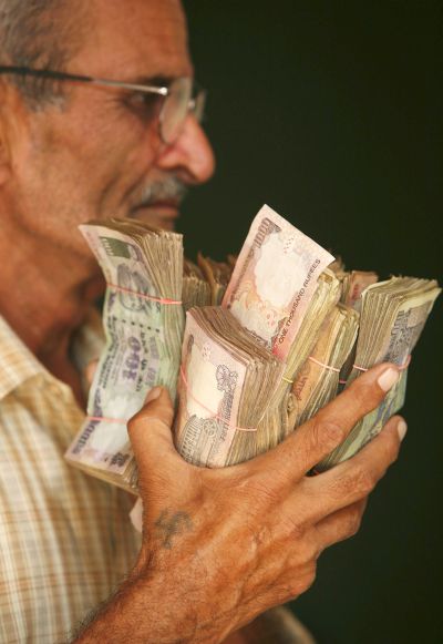 A man holds currency notes near a cash counter after withdrawing them inside a bank.
