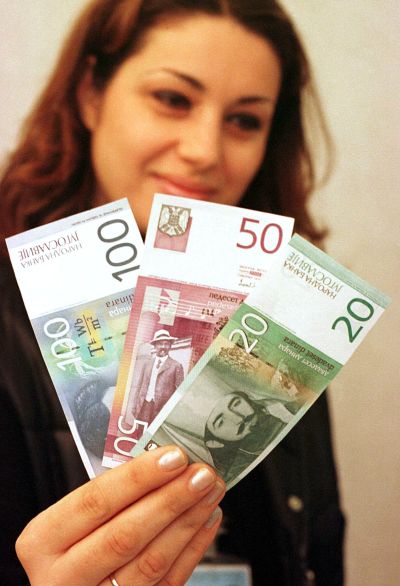 An employee shows three newly-designed banknotes.