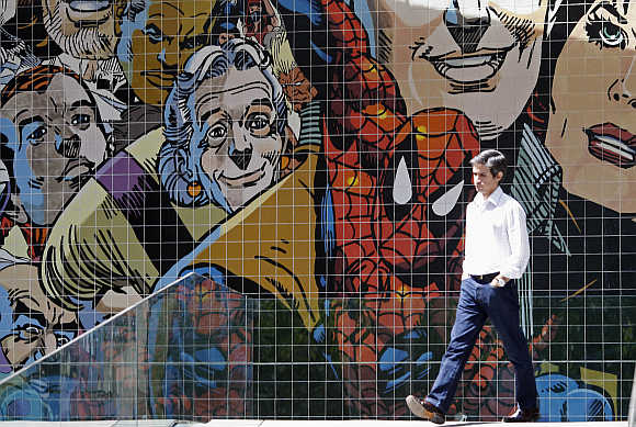 A man walks past a wall decorated with with comics characters on a street in Lisbon.