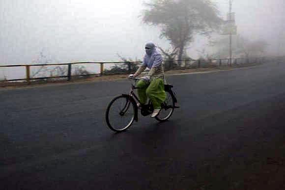 A girl cycles on a foggy and cold winter morning