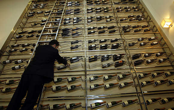A waiter arranges bottles of wine on a giant rack at a bar in Dubai.