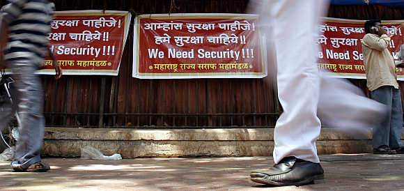 People walk past placards during a demonstration by jewellers and workers in Mumbai. Thousands of jewellers shut their stores and held a protest against a rise in burglaries and attacks on gold merchants.