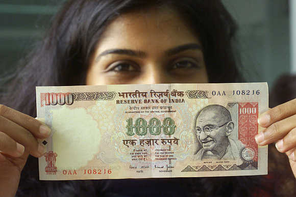 A girl displays a Rs 1,000 note in Mumbai.