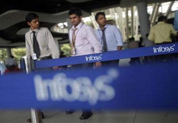 Employees of software company Infosys walk past Infosys logos at their campus.