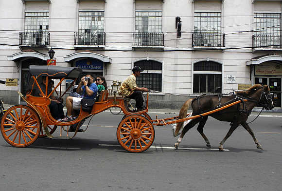 Tourists ride on a 'Kalesa', a horse drawn carriage, in Manila's historic Intramuros also known as 'Walled city' in the Philippines.