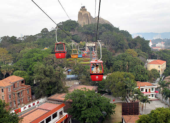 A tourist rides a cable car above old buildings, which date back to the 1920s and 1930s, in the southeastern Chinese city of Xiamen.