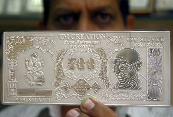 A jeweller displays a silver plate in the form of a rupee note.