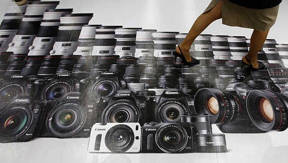 A woman walks on an advertisement for Canon digital cameras at an electronics retail store in Tokyo.