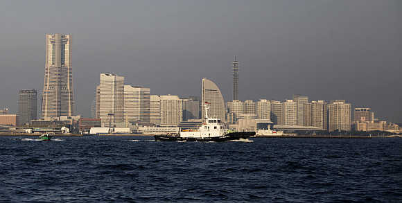 Ships sail against skyscrapers lining the background at Yokohama Bay in Yokohama.