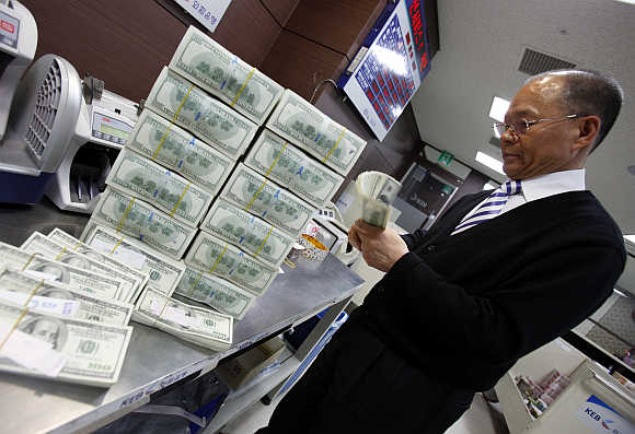 An employee of the Korea Exchange Bank counts one hundred dollar notes in Seoul, South Korea.
