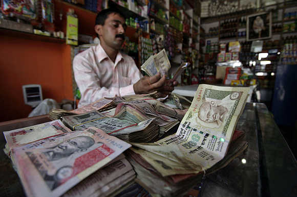 A shopkeeper counts currency notes inside his shop in Jammu.