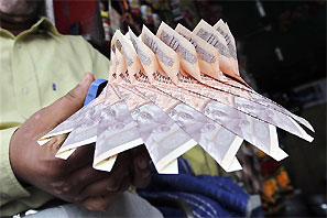 A Kashmiri shopkeeper staples together currency notes to make a garland at a market in Srinagar. Photograph: Fayaz Kabli/Reuters