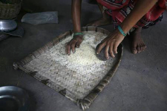 A woman sorts rice bought from a ration shop.