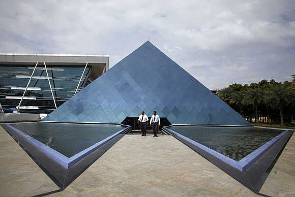 Employees walk in front of a pyramid-shaped building at the Infosys campus in the Electronic City area of Bengaluru.