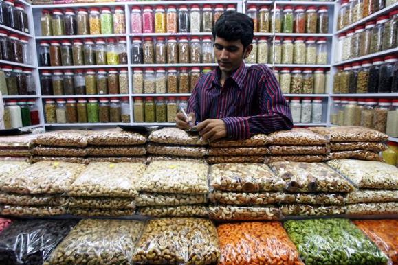 A shopkeeper does calculations standing in his nut and spice shop in Mumbai.
