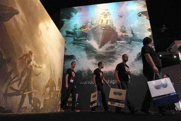 People pass exhibit artwork, including World of Warships, on the first day of E3 in Los Angeles, California.