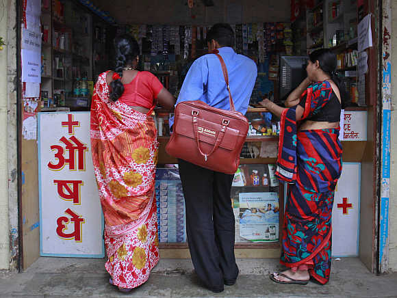 A medical representative, centre, talks to a chemist at a market in Pune.
