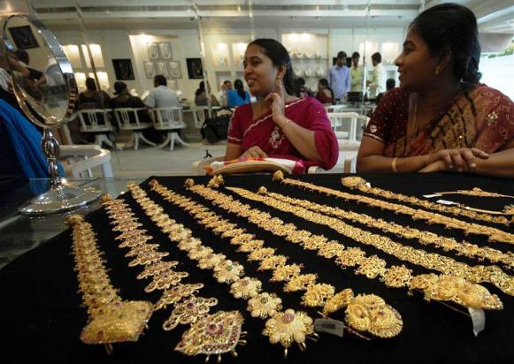 A customer looks in a mirror after wearing a gold earring inside a jewellery shop in Hyderabad.