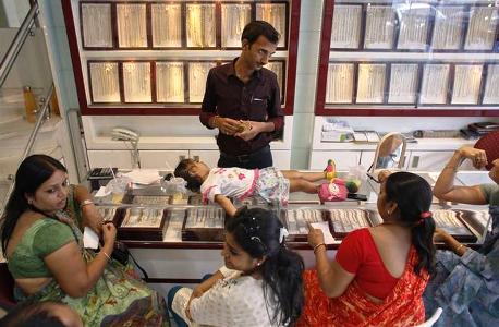 An employee counts money, as a child lies on the counter, following purchases of gold jewellery inside a showroom in Mumbai.