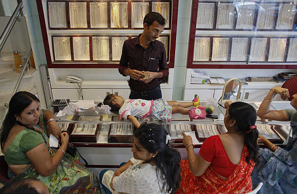 An employee counts money, as a child lies on a counter, inside a showroom in Mumbai.