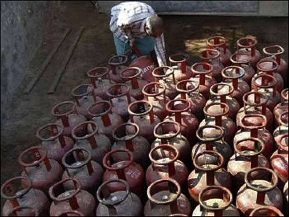 A worker collects LPG gas cylinders.