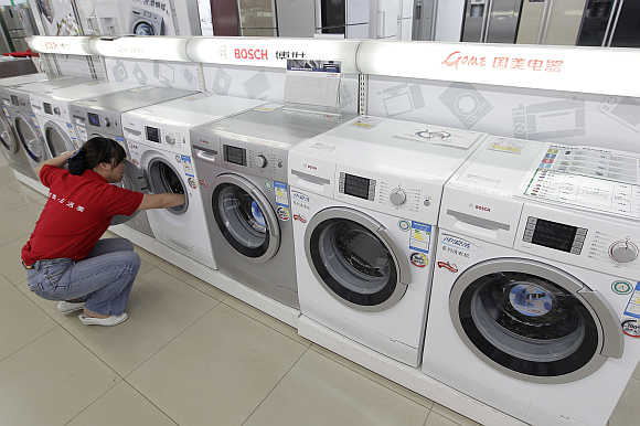 A sales assistant cleans a washing machine at an electrical appliance shop in Wuhan, Hubei province, China.