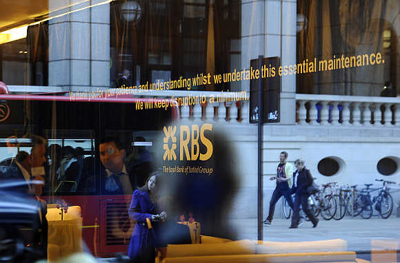 Pedestrians are reflected in the window of a Royal Bank of Scotland building in the City of London.