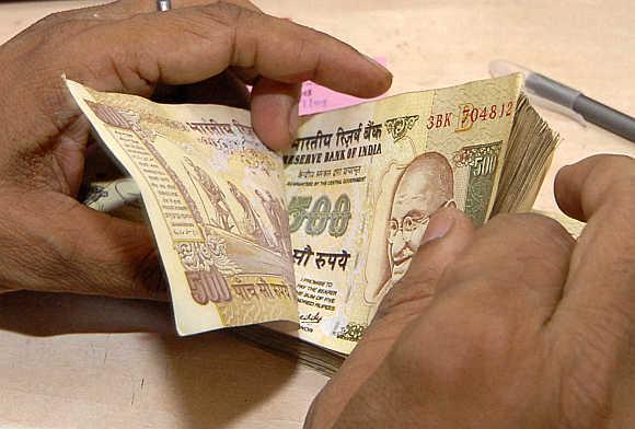 A cashier counts rupee notes inside a bank in Lucknow.