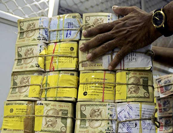 A bank employee counts bundles of rupee notes at a cash counter in Agartala, Tripura.