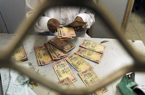 An employee sorts rupee notes at a cash counter inside a bank in Agartala, Tripura.