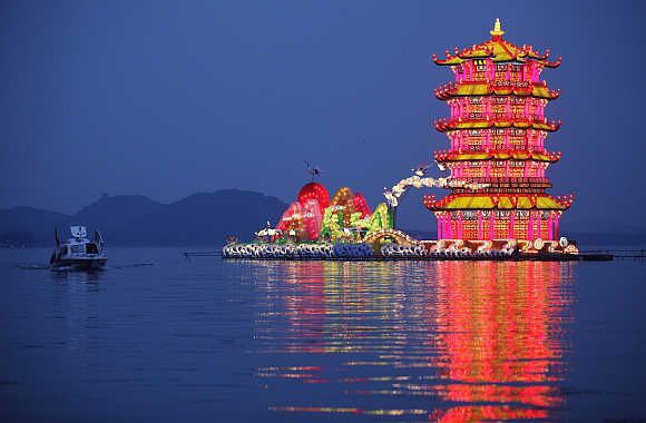 A tourist boat rows past a group of lanterns, featuring the Yellow Crane Tower, during the lighting test period of the Wuhan-Chengdu International Panda Lantern Festival on Donghu lake in Wuhan, Hubei province.