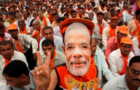 A BJP supporter wears a Narendra Modi mask at a rally.