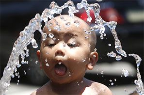 A boy cools off with water from a hose. Photograph: Reuters