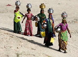 Women carrying empty pitchers walk to draw water from a well. Photograph: Reuters